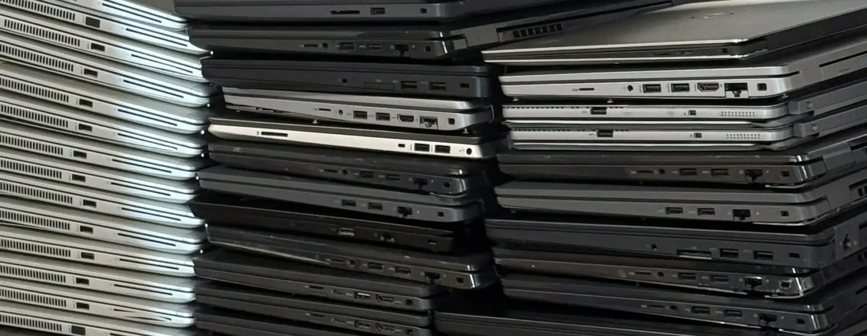 Pile of laptop computers stacked in multilevel towers on a table or shelf.